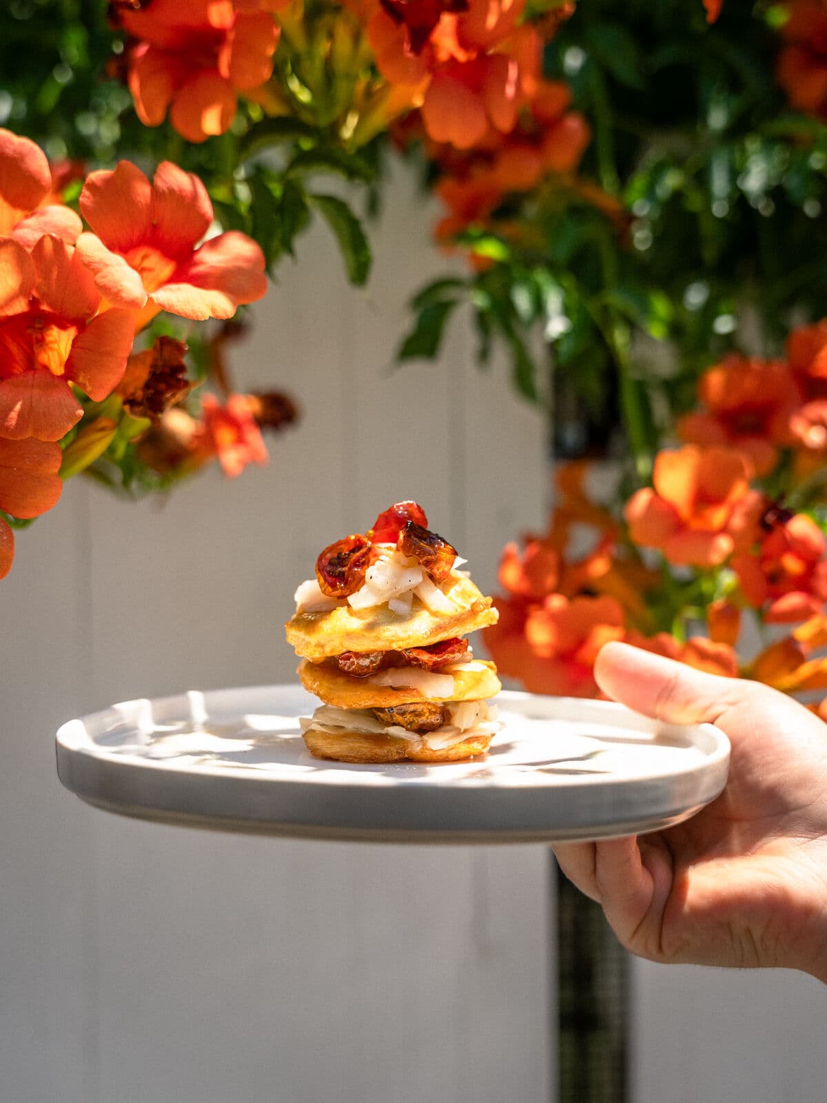 Un piatto servito in giardino, davanti a fiori arancioni