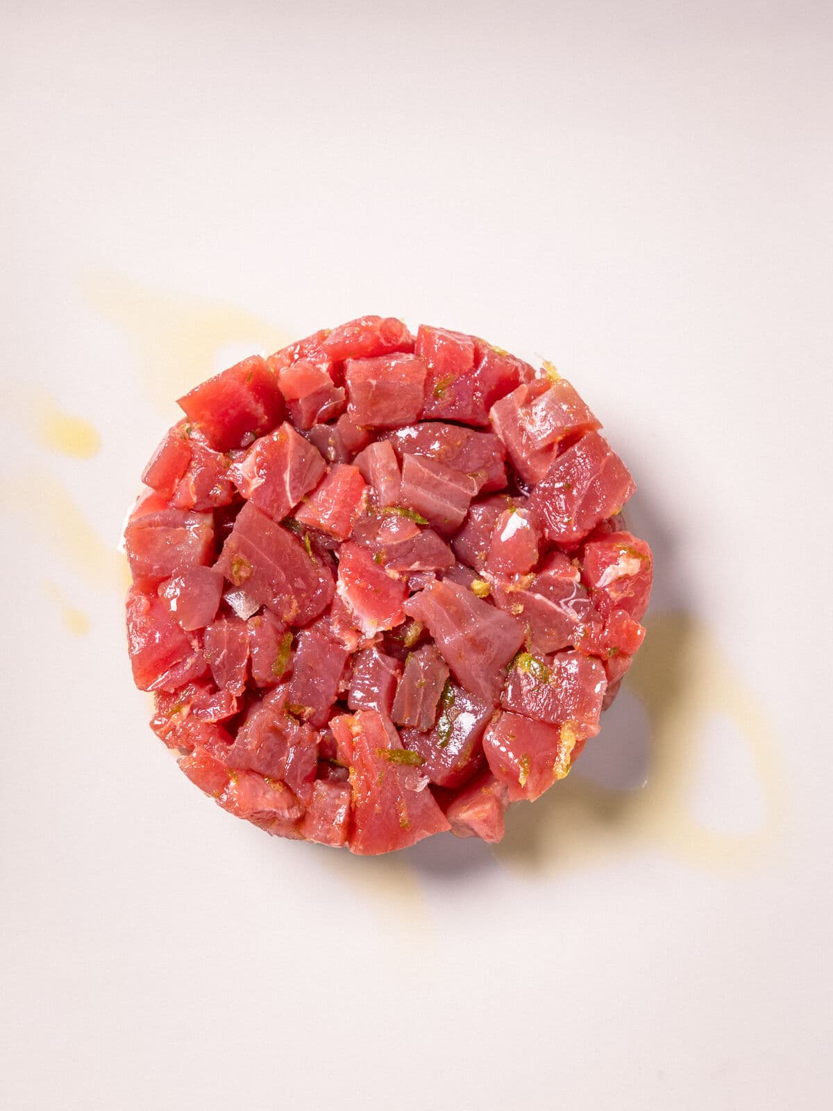 Una tartare a cubetti, cruda, in un piatto bianco visto dall'alto
